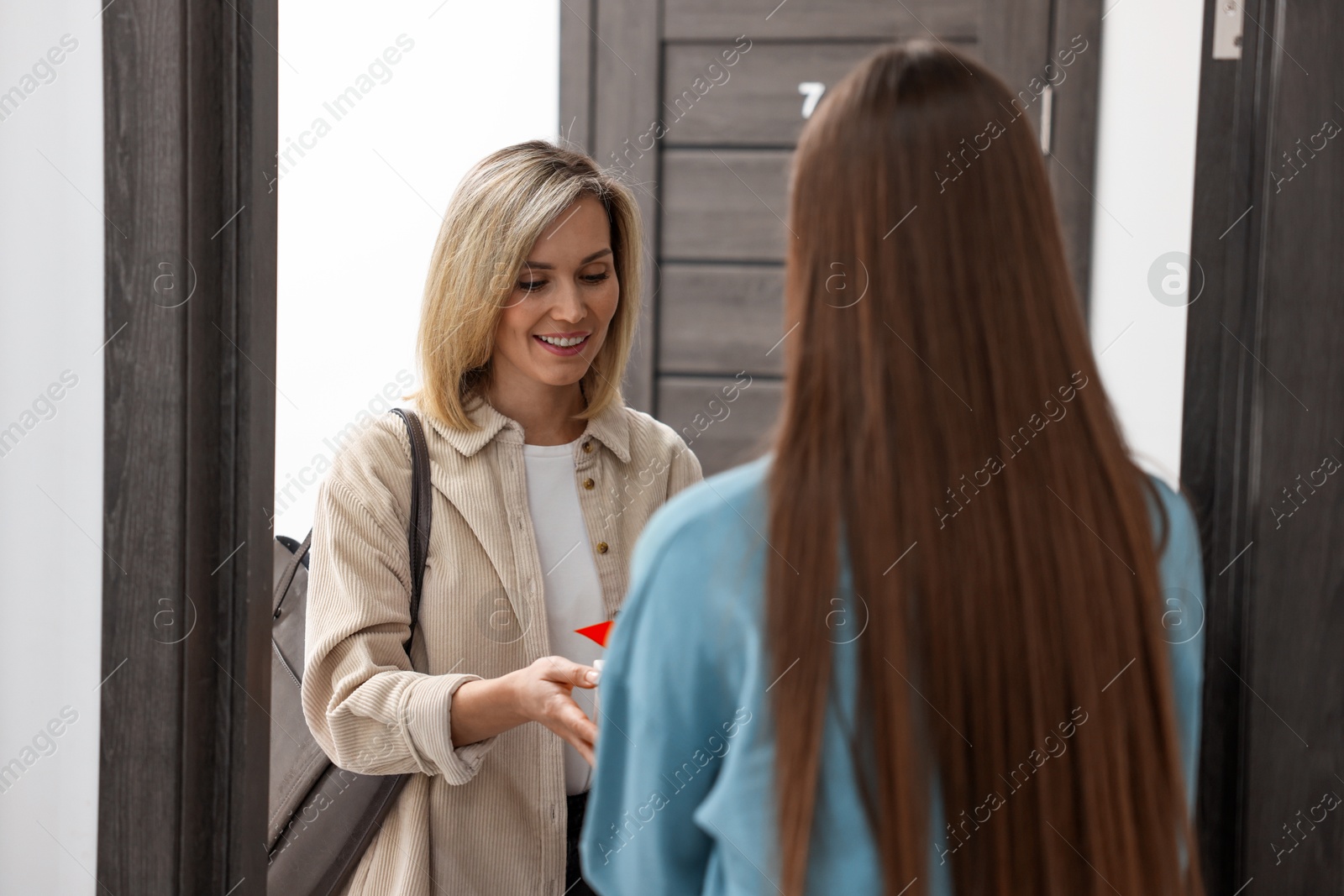 Photo of Woman giving housewarming gift to her friend at new apartment