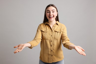 Woman welcoming friends or guests on grey background