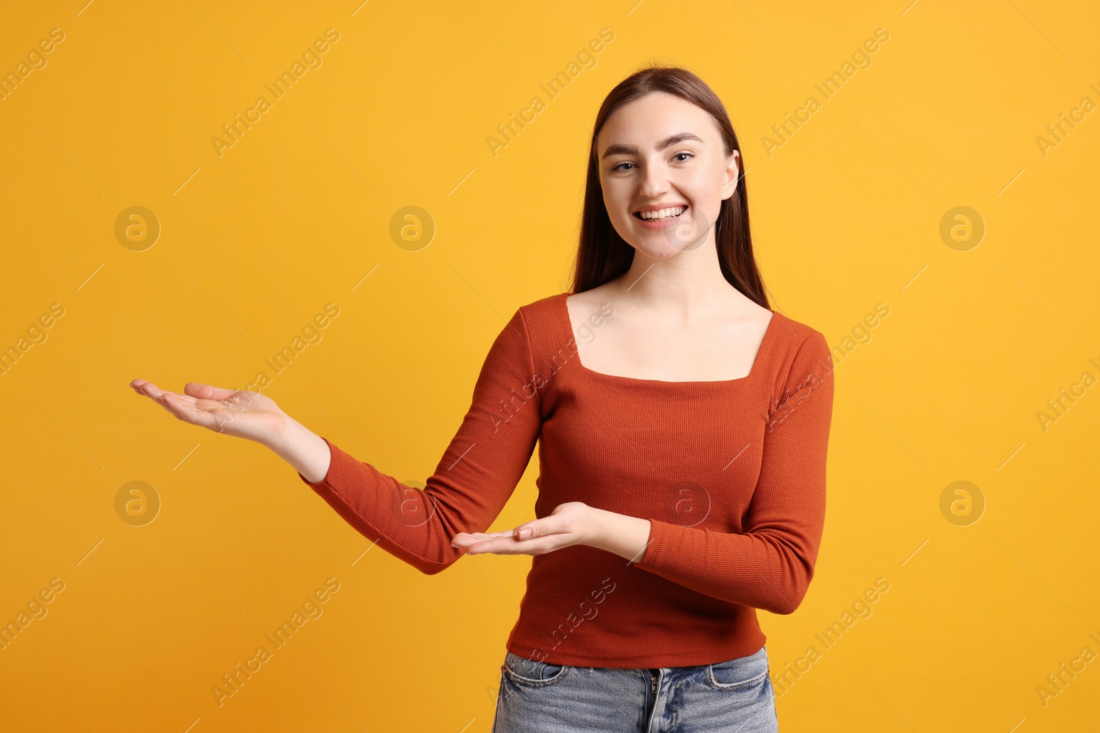 Photo of Happy woman welcoming guests on orange background