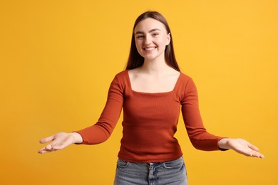 Happy woman welcoming guests on orange background