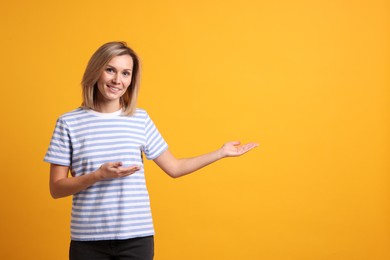 Photo of Happy woman welcoming guests on orange background. Space for text