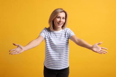 Happy woman welcoming guests on orange background