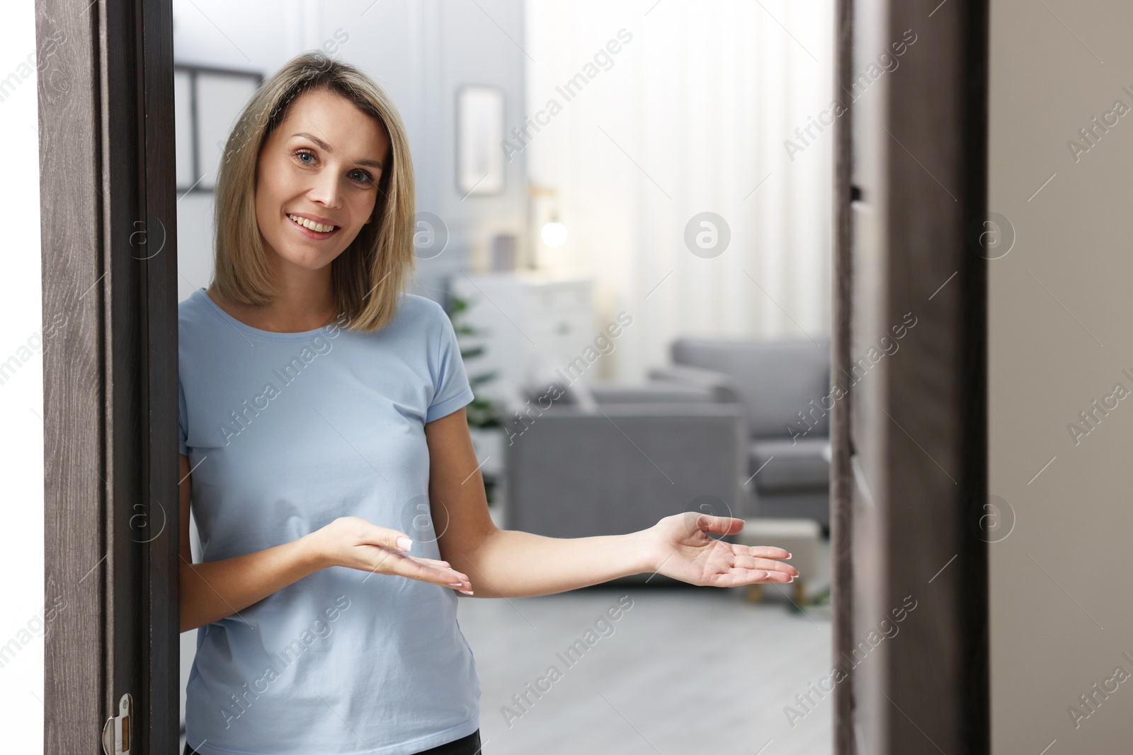 Photo of Happy woman welcoming guests to her house