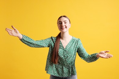 Cheerful woman welcoming guests on orange background