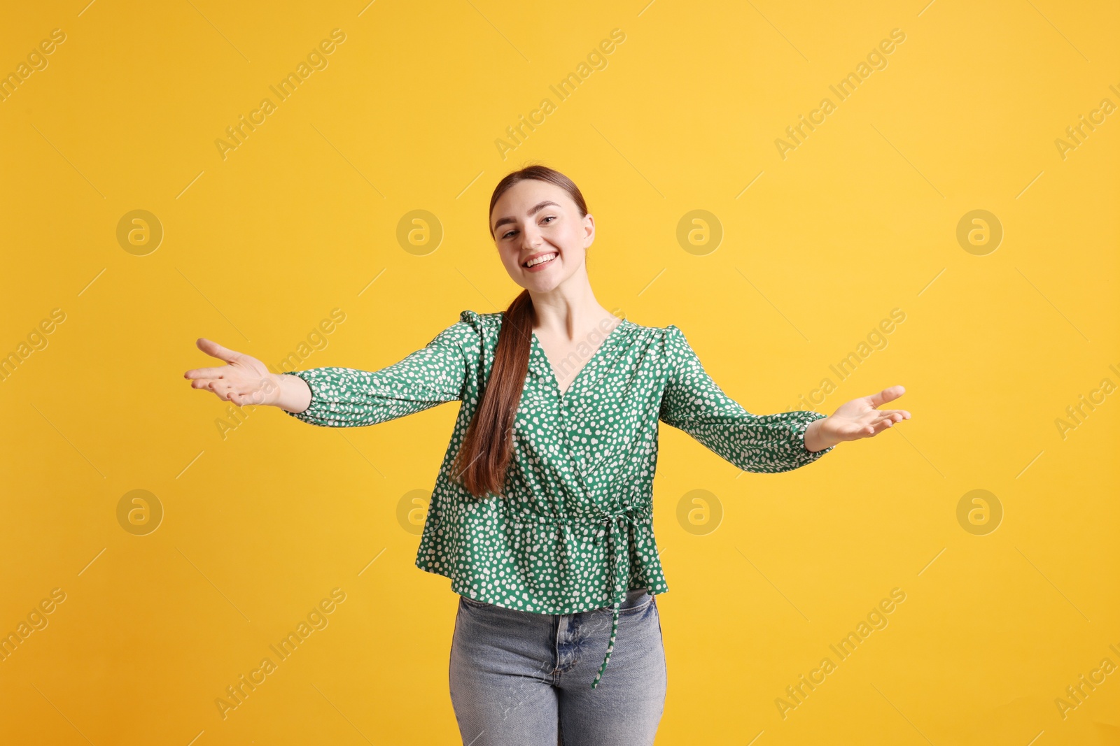 Photo of Cheerful woman welcoming guests on orange background