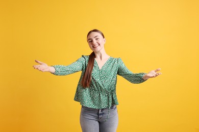 Photo of Cheerful woman welcoming guests on orange background