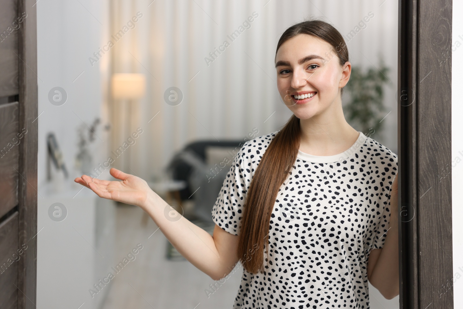 Photo of Happy woman welcoming guests to her house