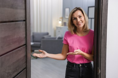 Photo of Happy woman welcoming guests to her house