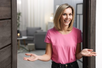 Photo of Happy woman welcoming guests to her house