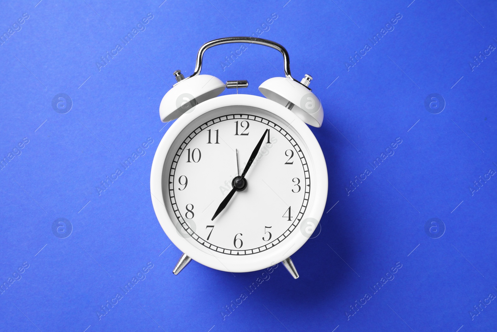 One white alarm clock on blue background, top view Photo of One white alarm clock on blue background, top view