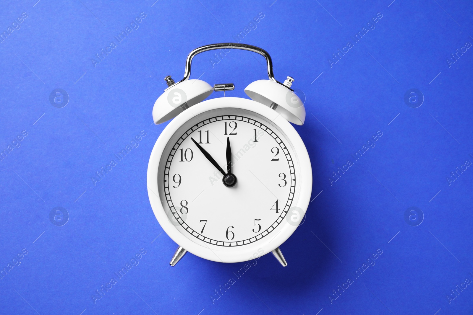 One white alarm clock on blue background, top view Photo of One white alarm clock on blue background, top view