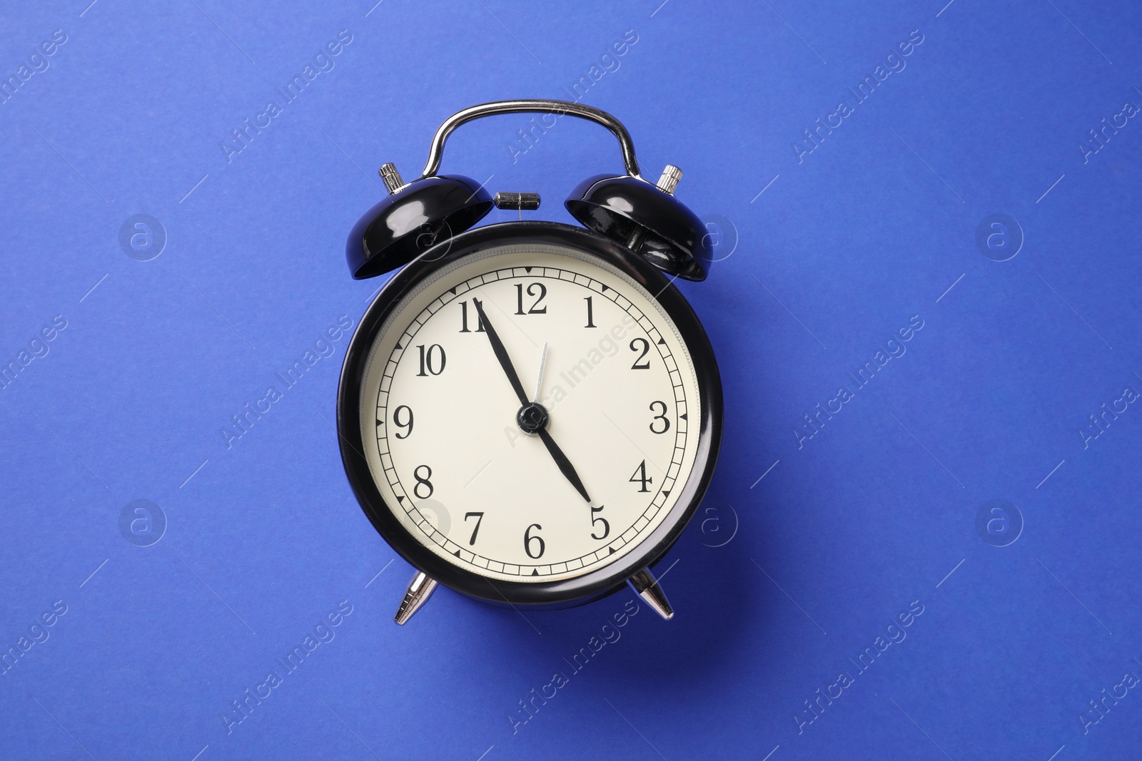 One black alarm clock on blue background, top view Photo of One black alarm clock on blue background, top view
