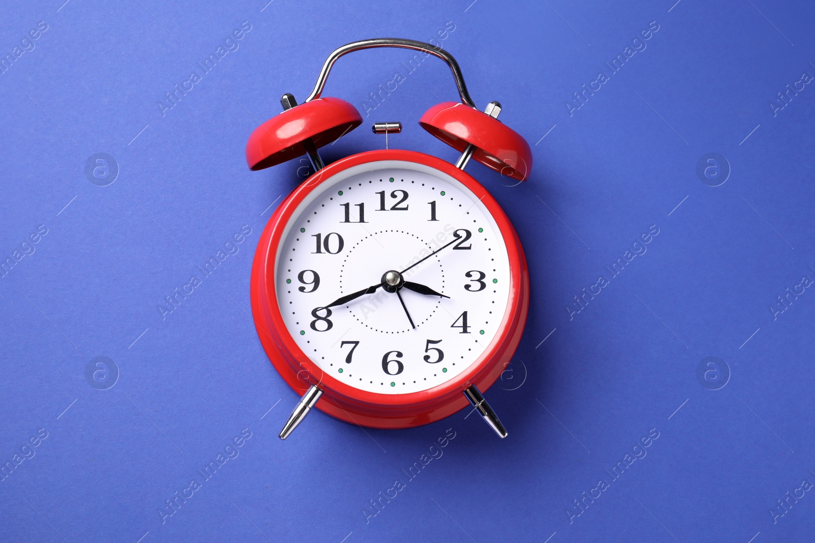 One red alarm clock on blue background, top view Photo of One red alarm clock on blue background, top view