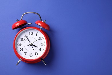 Photo of One red alarm clock on blue background, top view. Space for text