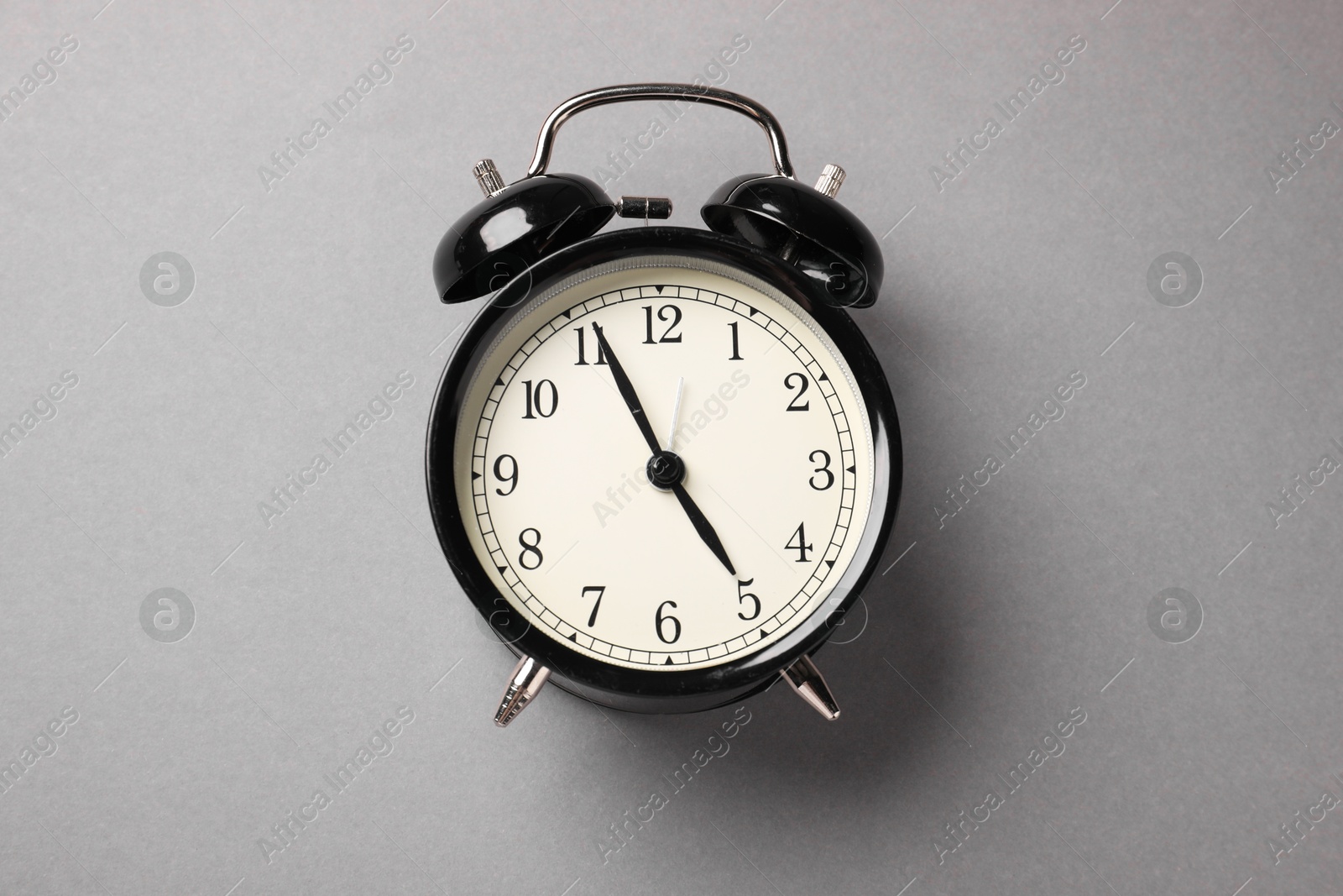 Photo of One black alarm clock on light grey background, top view
