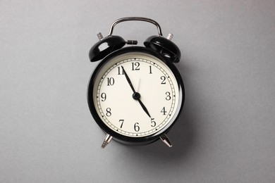 Photo of One black alarm clock on light grey background, top view