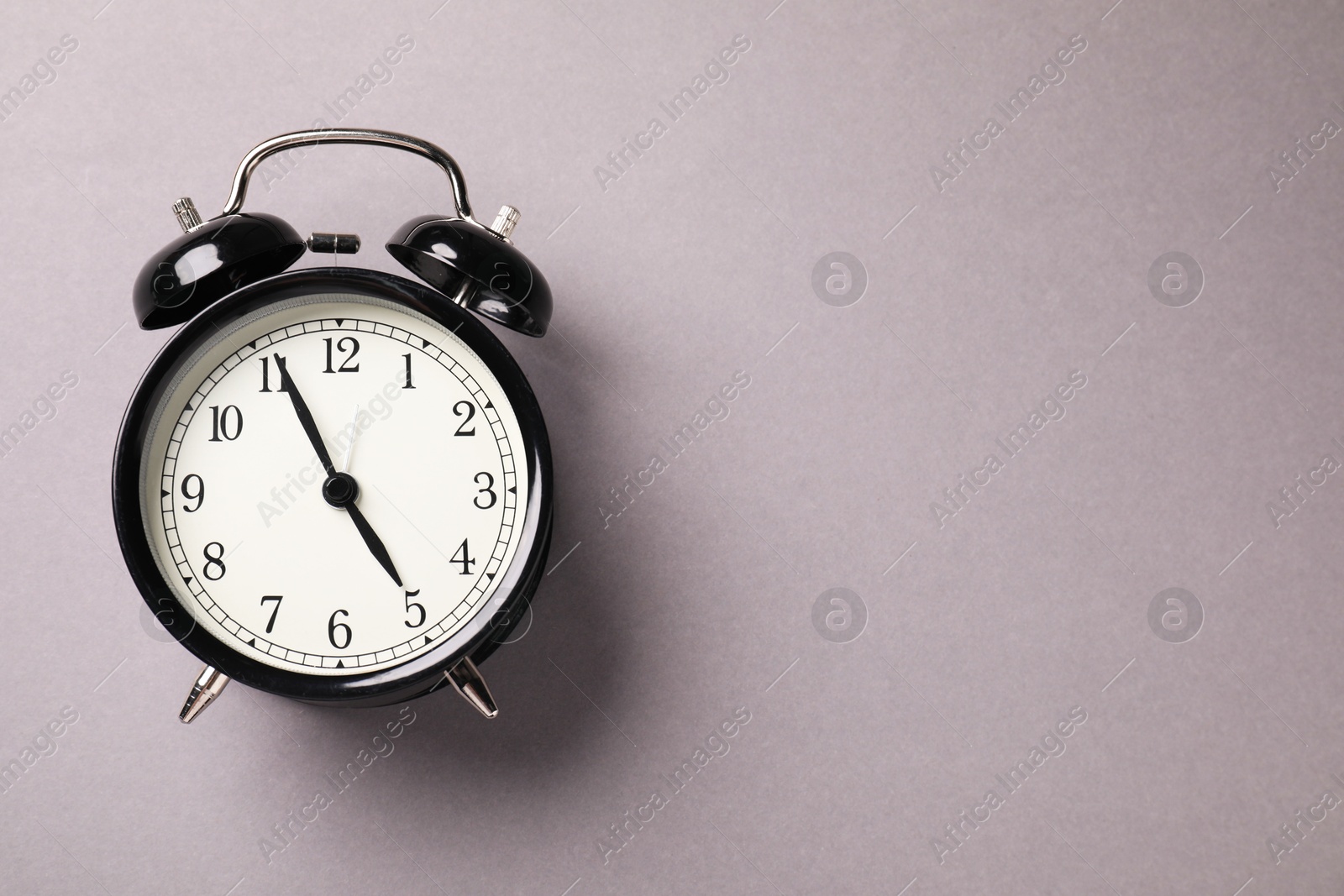 Photo of One black alarm clock on light grey background, top view. Space for text