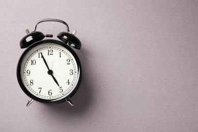 Photo of One black alarm clock on light grey background, top view. Space for text