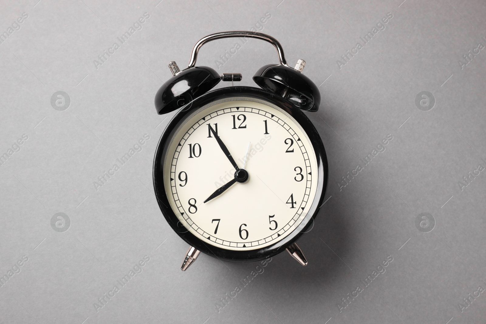 Photo of One black alarm clock on light grey background, top view