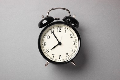 Photo of One black alarm clock on light grey background, top view