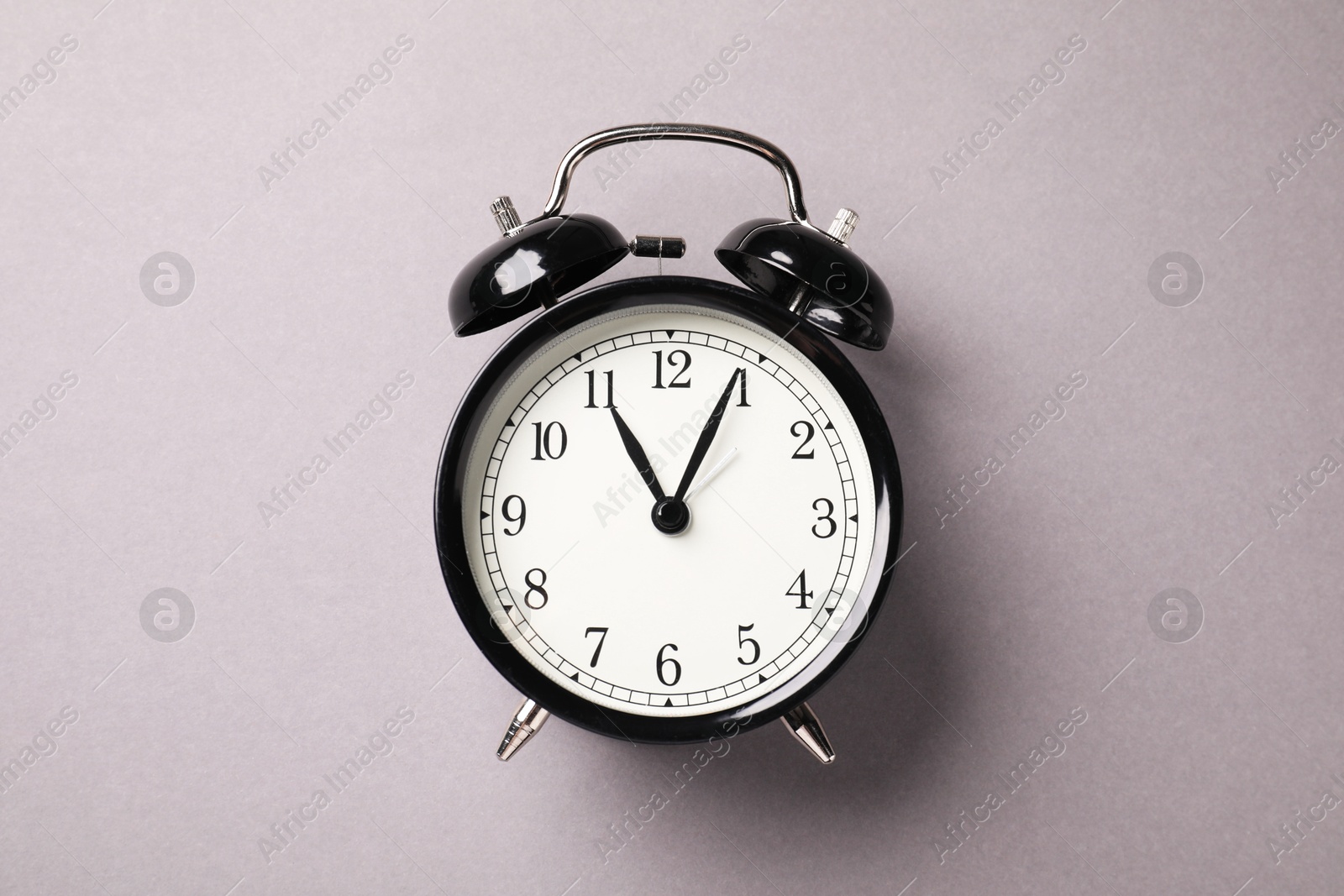 Photo of One black alarm clock on light grey background, top view