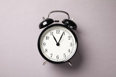 Photo of One black alarm clock on light grey background, top view