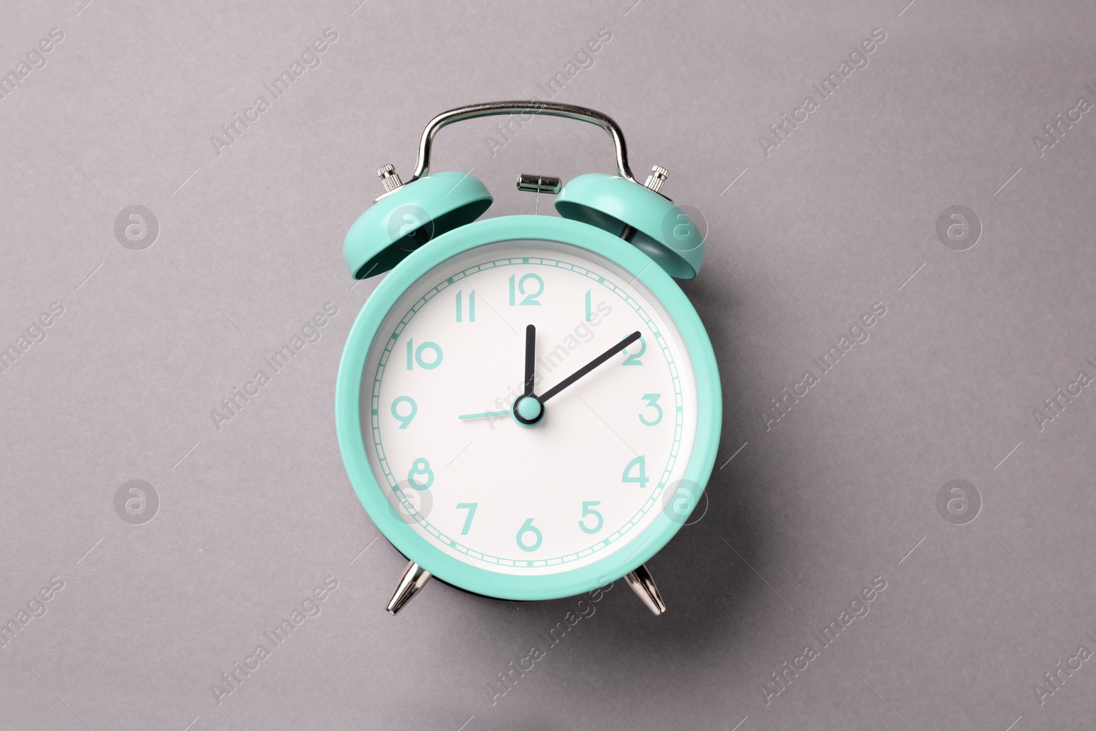 Photo of One turquoise alarm clock on light grey background, top view
