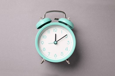 Photo of One turquoise alarm clock on light grey background, top view