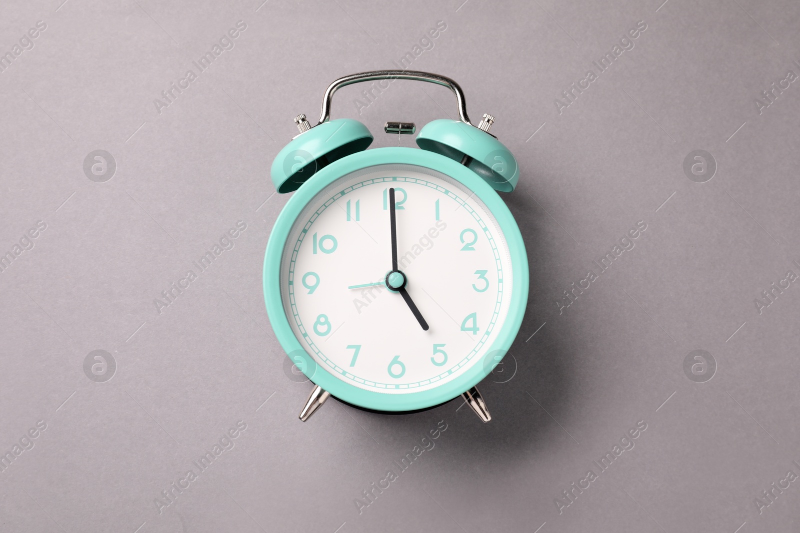 Photo of One turquoise alarm clock on light grey background, top view