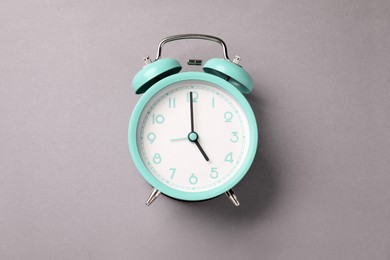 Photo of One turquoise alarm clock on light grey background, top view