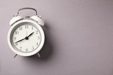 Photo of One white alarm clock on light grey background, top view. Space for text