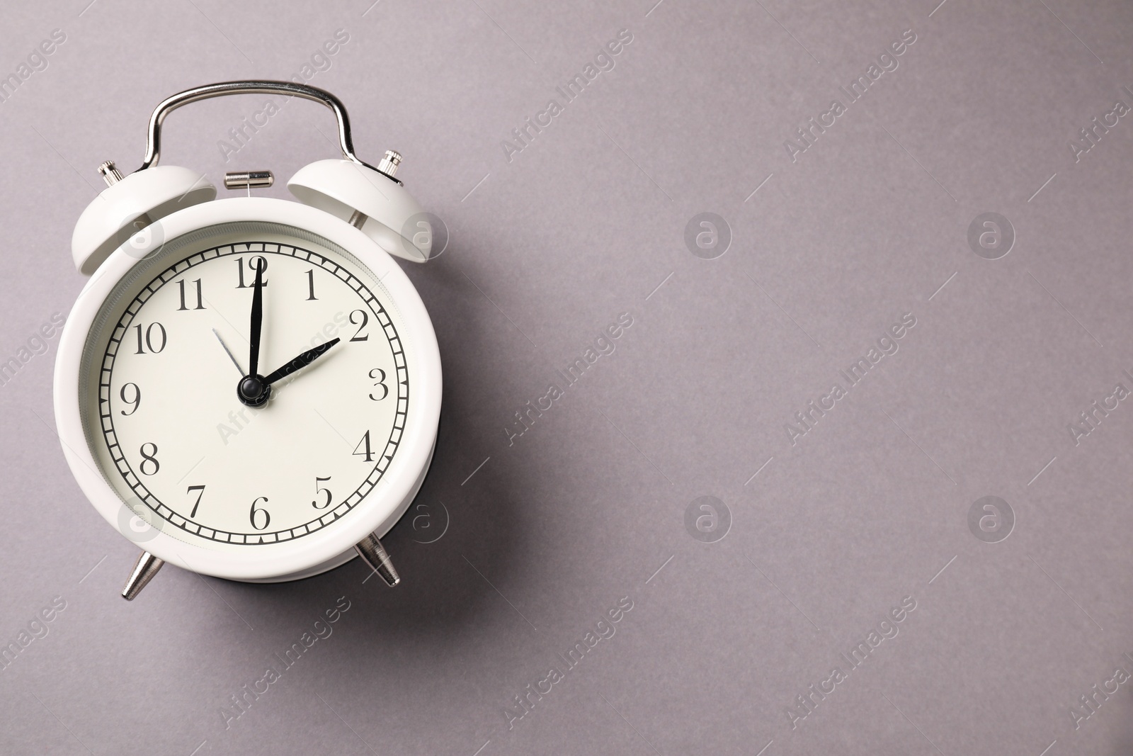 Photo of One white alarm clock on light grey background, top view. Space for text