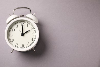 Photo of One white alarm clock on light grey background, top view. Space for text
