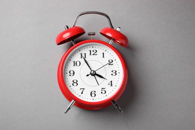 Photo of One red alarm clock on light grey background, top view