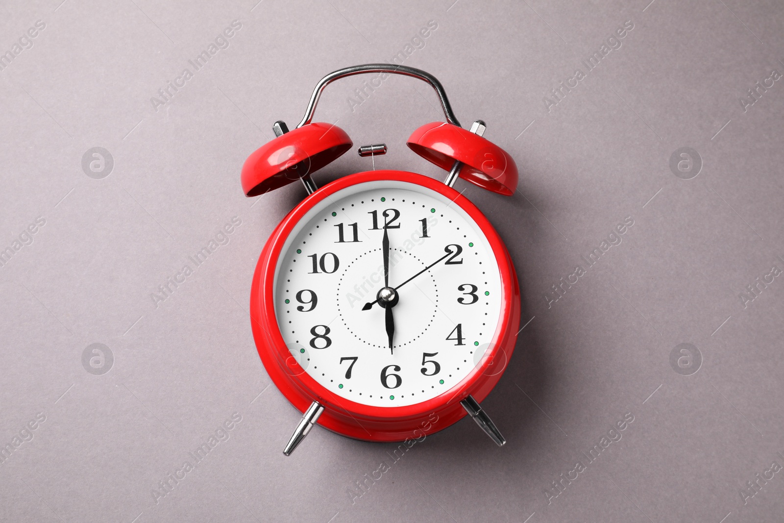 Photo of One red alarm clock on light grey background, top view