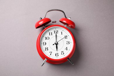 Photo of One red alarm clock on light grey background, top view