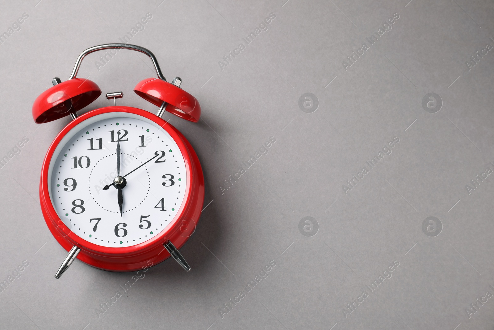 Photo of One red alarm clock on light grey background, top view. Space for text