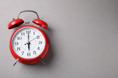 Photo of One red alarm clock on light grey background, top view. Space for text