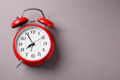 Photo of One red alarm clock on light grey background, top view. Space for text