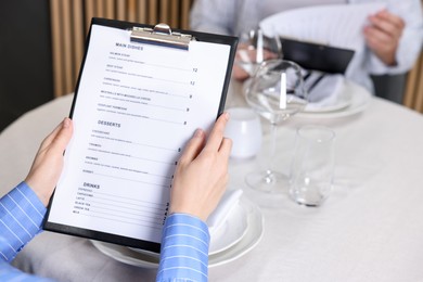 Photo of Couple choosing dishes from menu at table in restaurant, closeup