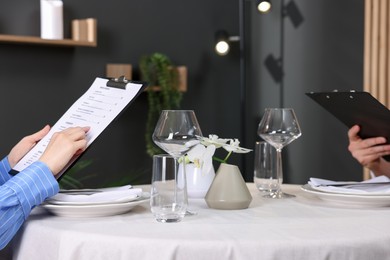 Photo of Couple choosing dishes from menu at table in restaurant, closeup