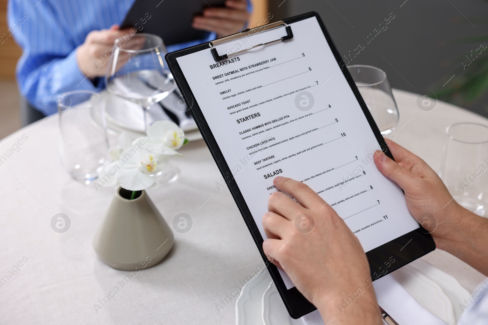 Photo of Couple choosing dishes from menu at table in restaurant, closeup