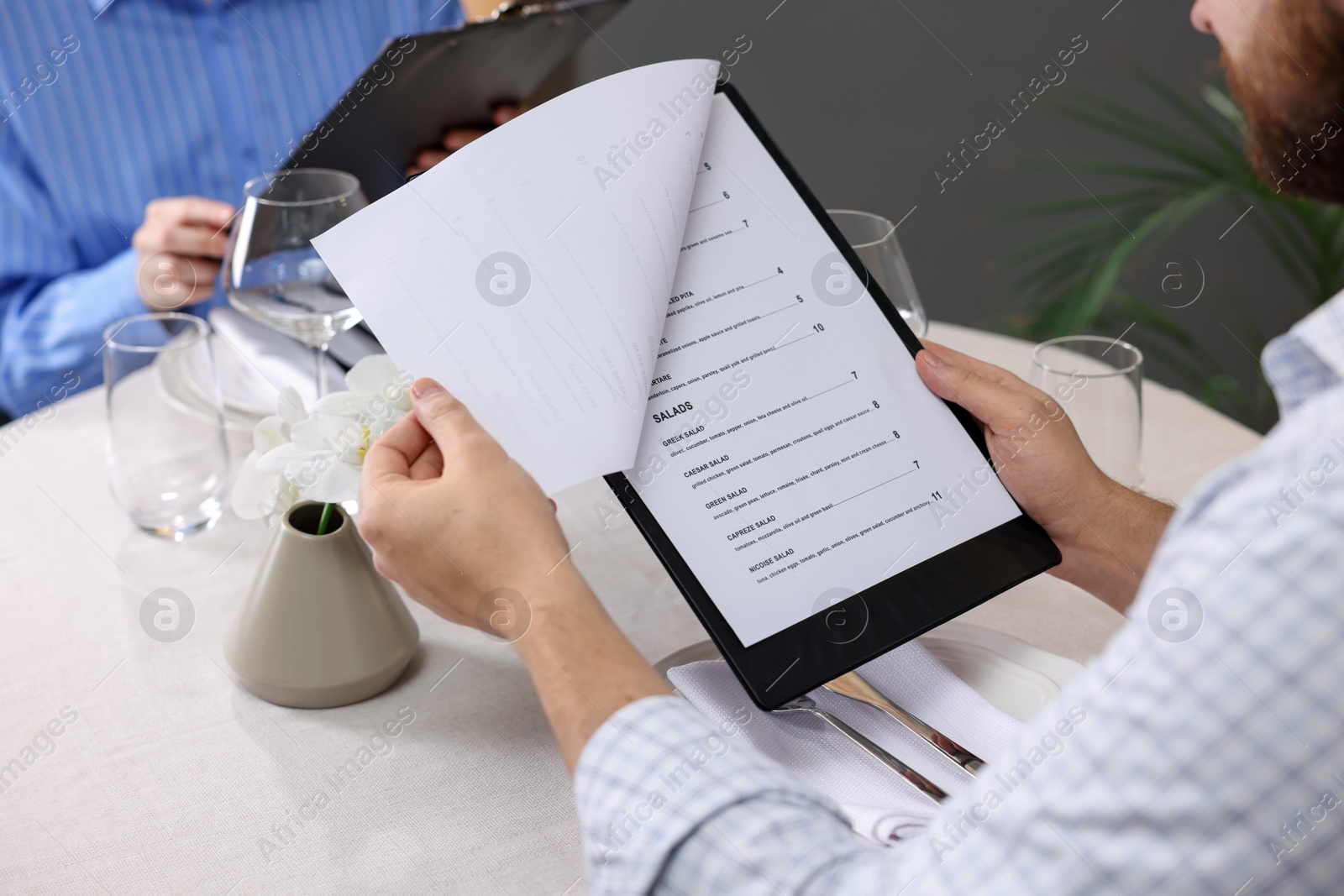 Photo of Couple choosing dishes from menu at table in restaurant, closeup