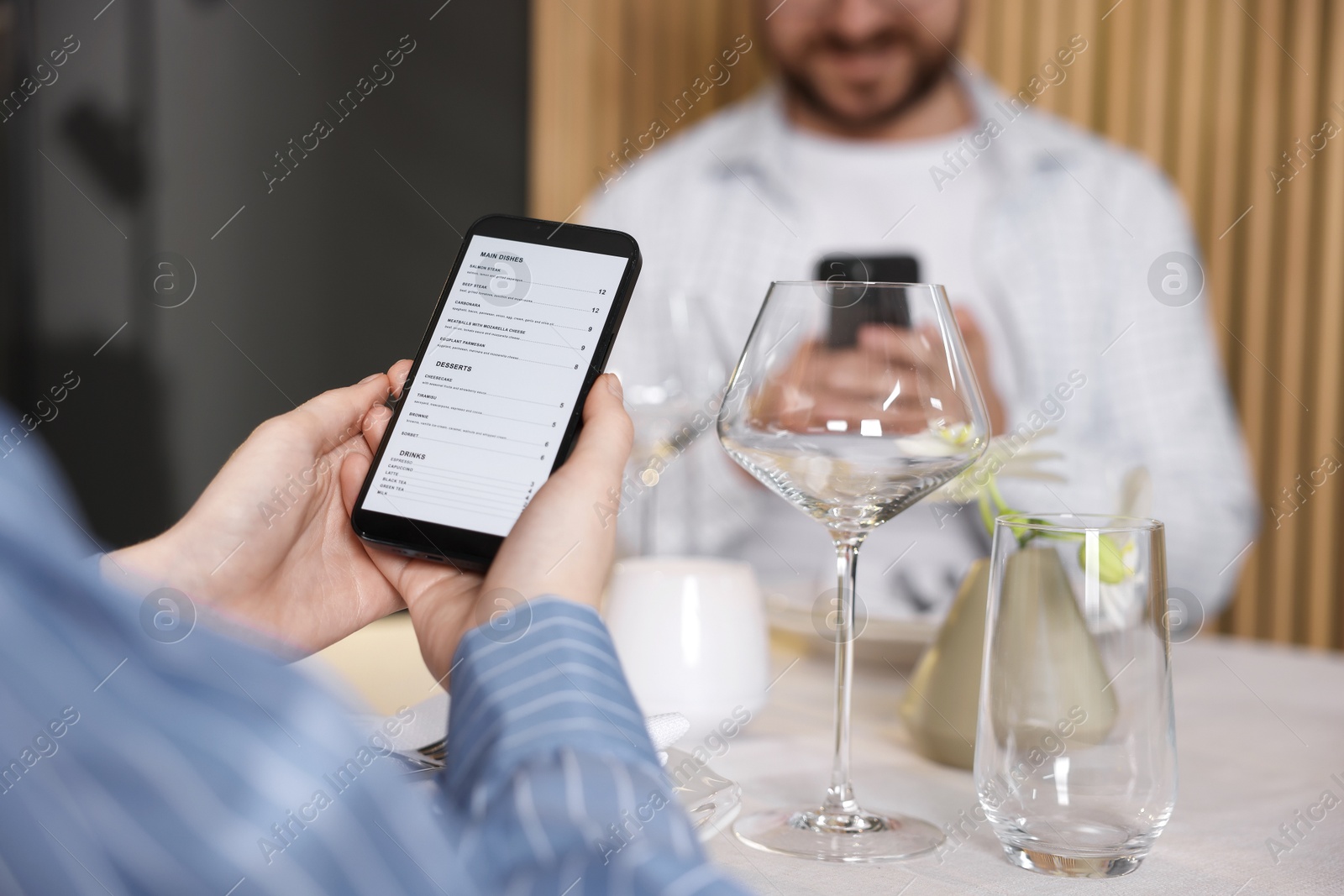 Photo of Couple choosing dishes from digital menu at restaurant, closeup