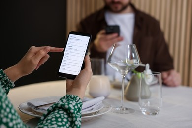 Photo of Couple choosing dishes from digital menu at restaurant, closeup