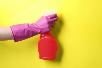 Photo of Woman with spray bottle of cleaning product on yellow background, closeup. Space for text