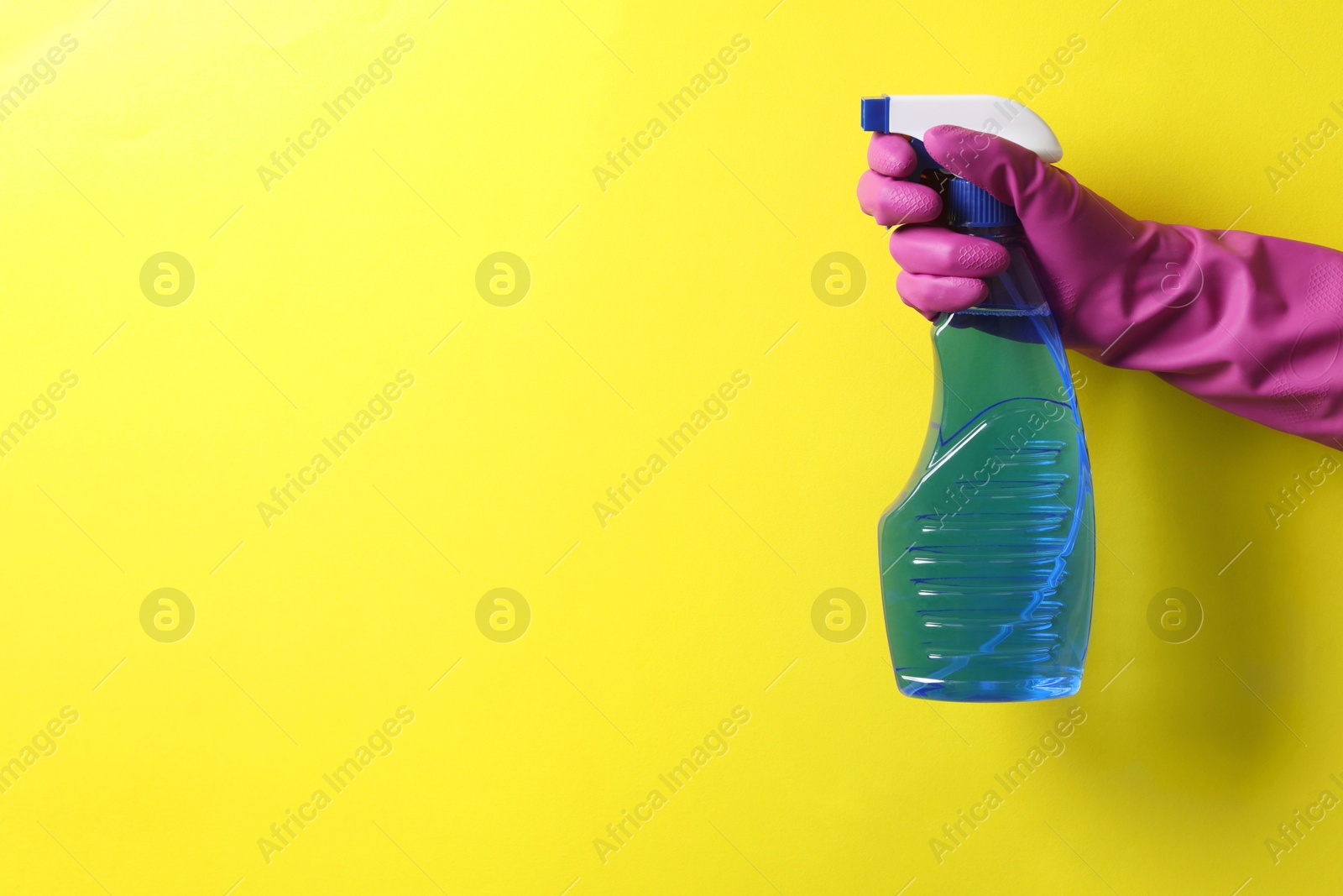 Photo of Woman with spray bottle of cleaning product on yellow background, closeup. Space for text