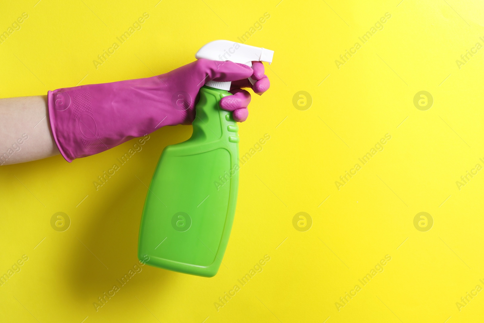 Photo of Woman with spray bottle of cleaning product on yellow background, closeup. Space for text