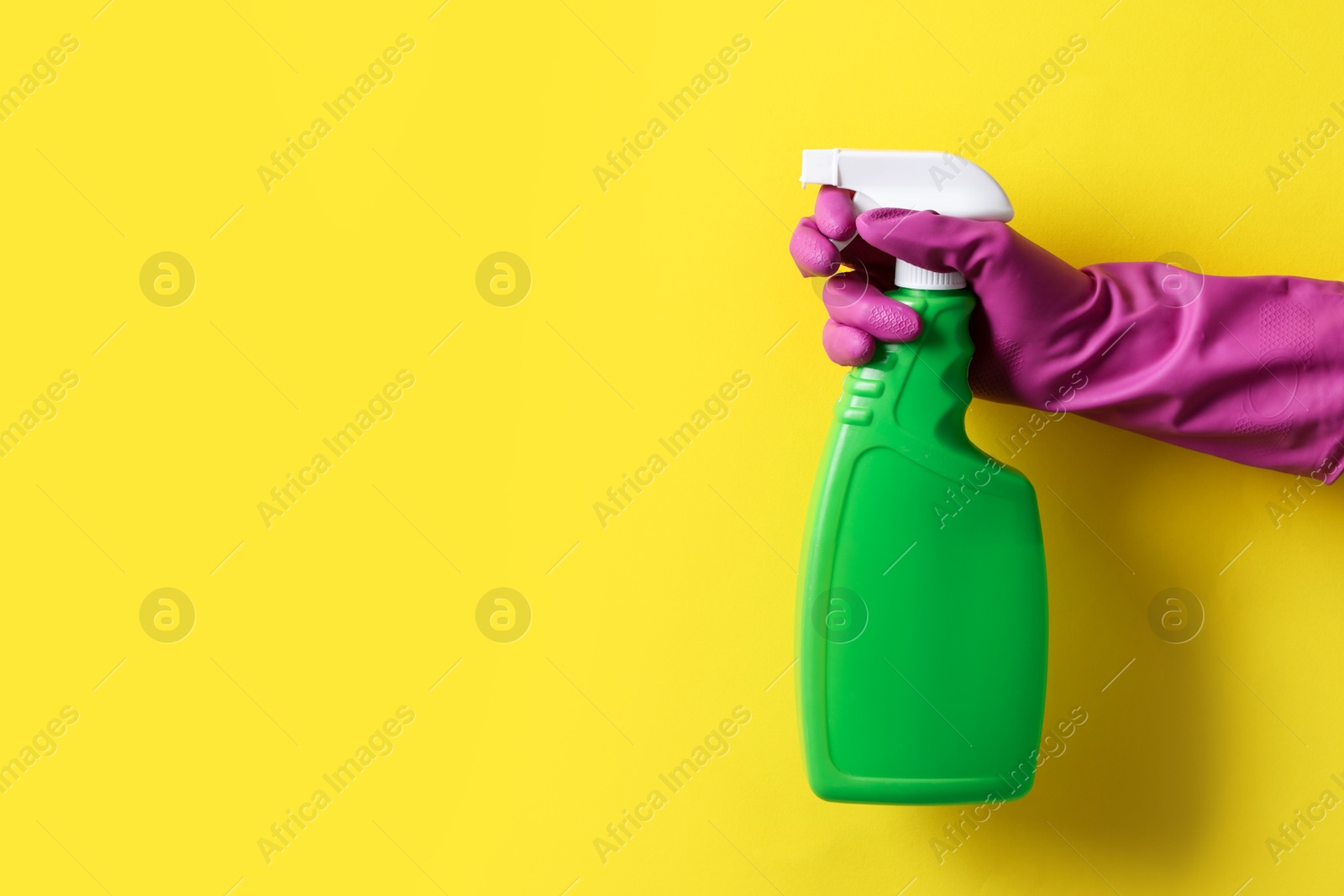 Photo of Woman with spray bottle of cleaning product on yellow background, closeup. Space for text