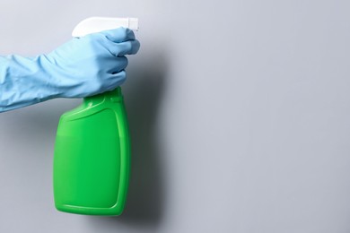 Photo of Woman with spray bottle of cleaning product on light grey background, closeup. Space for text